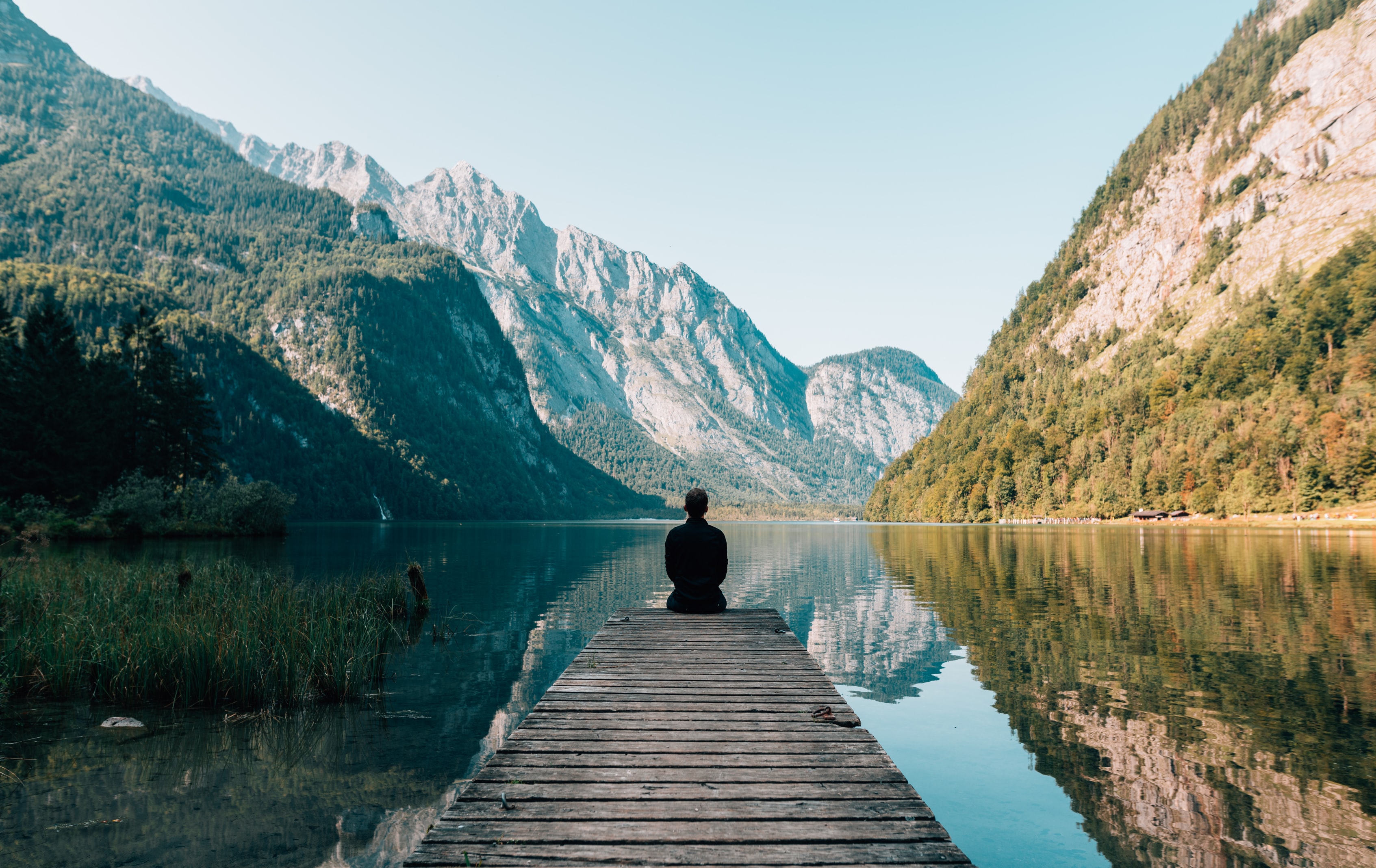 A person sitting on a dock in front of a beautiful landscape